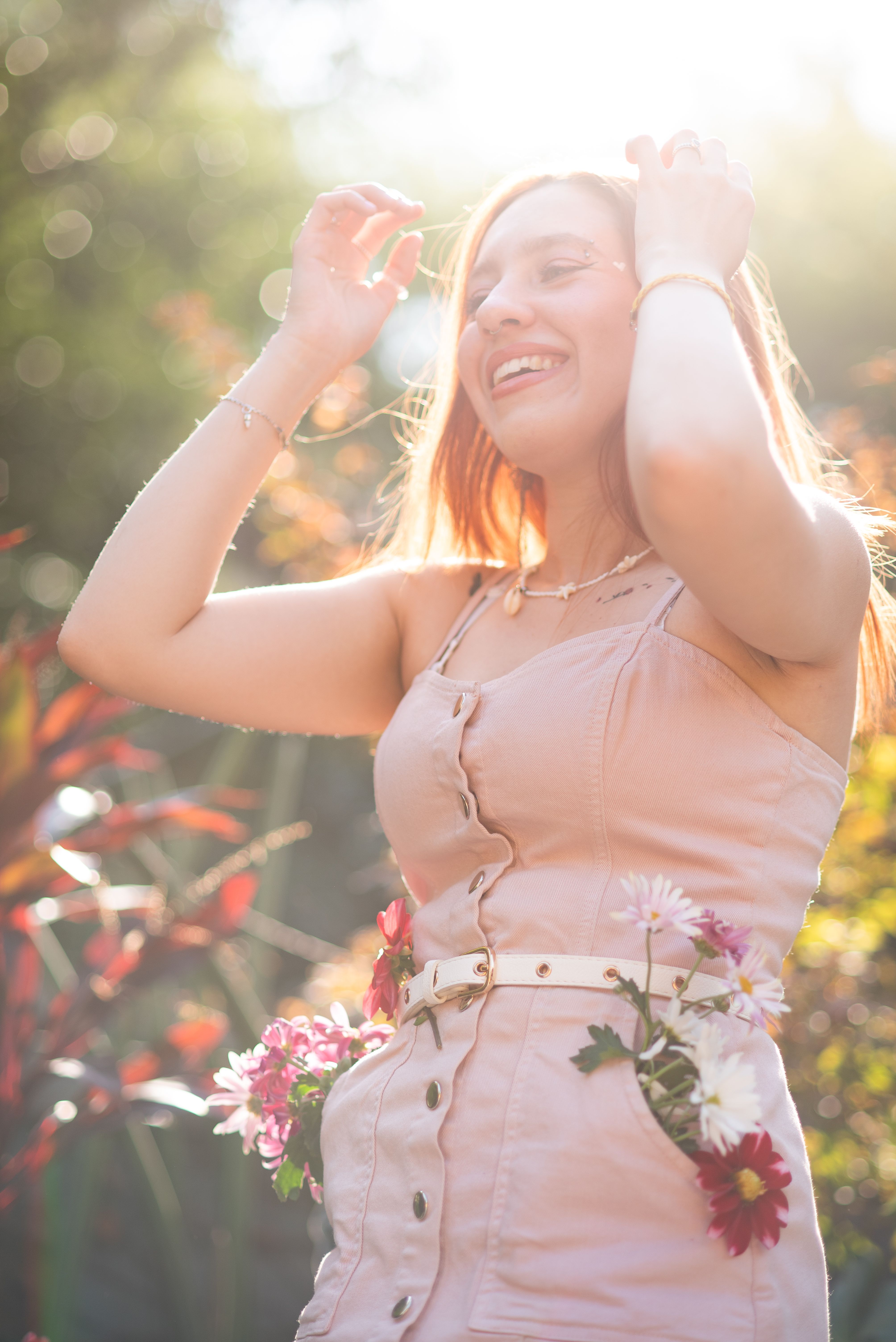 Mujer sonriente entre flores bajo una cálida luz dorada